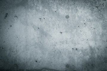 Gray concrete wall texture surface dark background with vignetting. A coarse facade made of natural cement with holes and imperfections as an empty rustic cold sterile empty space backdrop.