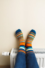legs with colorful socks on heating radiator