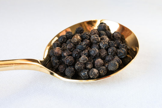 Black Peppercorns on a Gold Spoon
