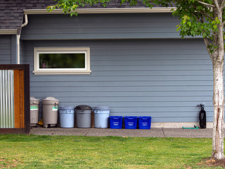 street scene, garbage cans and recycling tubs at side of blue house