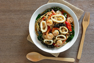 top view of stir fried sizzle seafood in a ceramic dish on wooden table. asian homemade style food concep