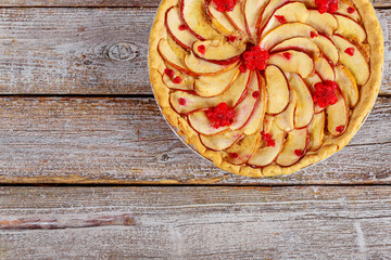 Apple pie with sliced apples on the top on wooden background