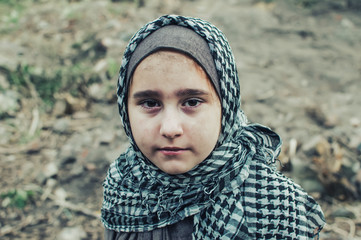 a refugee child in the war, a Muslim girl with a dirty face on the ruins, the concept of peace and...
