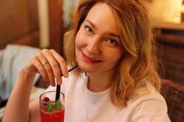 Charming woman enjoying non-alcoholic cocktail. Close-up portrait in warm tones. Holiday concept