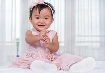 baby in pink dress on bed
