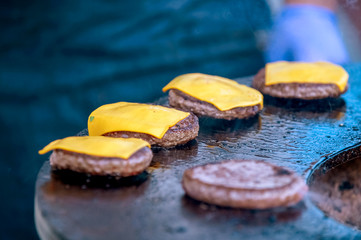 grilling hamburger patties with cheese in smoke open air