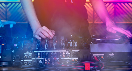 Hands of EDM DJ plays and controls the disc at the turntable. Party concept at the nightclub.