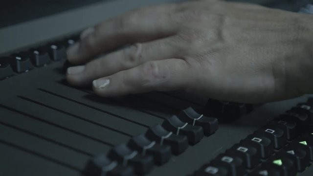Close-up of fingers and knobs on sound control panel during a live-show.