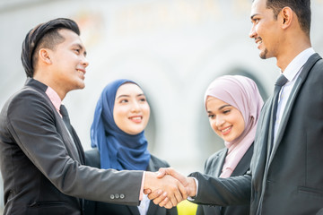 Welcome onboard! Muslim Asian business people shaking hands with new partner, business co-working teamwork concept.