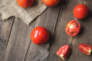 tomato fruits and sliced pieces on a wooden board.