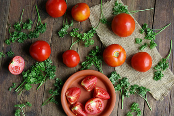 tomato fruits and sliced pieces on a wooden board.