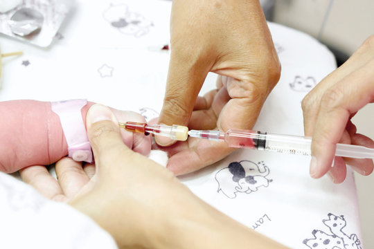 Image of a nurse hands is using a syringe gradually vaccinate on sick newborn baby's hand.