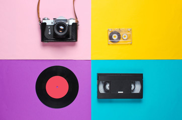 Retro top view still life. Vinyl record, vintage film camera, video and audio cassette on blue...