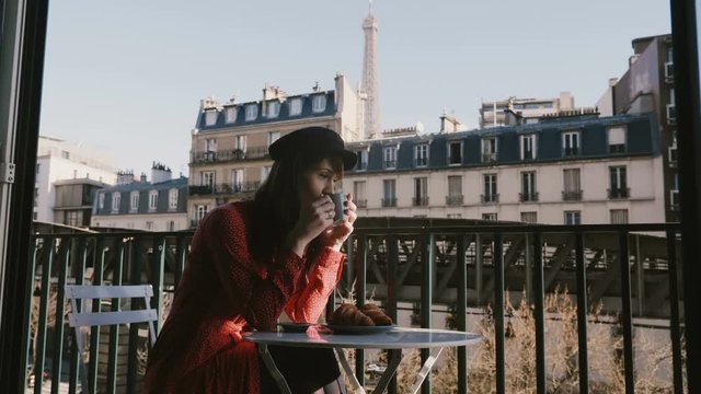 Happy beautiful relaxed tourist woman enjoying coffee and breakfast at French morning cafe patio with Eiffel Tower view.