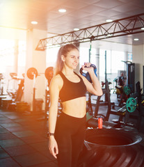 Fototapeta premium Young woman in sportswear lifts the kettlebell with one hand standing in the gym. Functional training