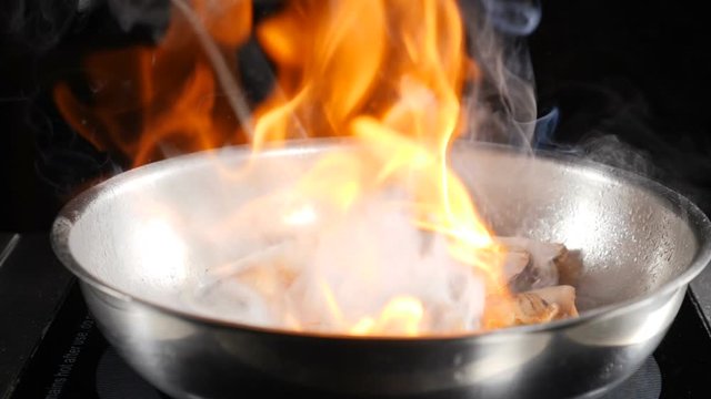 Food video in slow motion. Seafood cooking by chef in restaurant. preparing of Italian Seafood flambe using Shrimp, Clams, Mussels in dish. Italian cuisine concept. hd