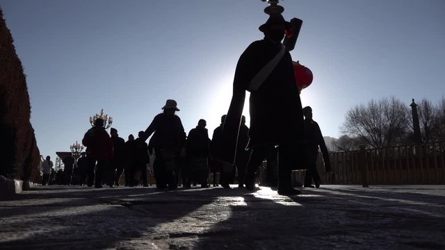 Slow motion video of silhouttes of pilgrims walking around Potala Palace, religion and traditional culture in Lhasa, Tibet