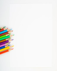 Background of colour pencils at the corner of blank drawing paper for kids study and learn art when back school on isolated background.