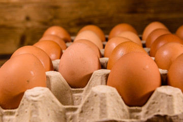 Pile of the hen eggs in paper tray on wooden table