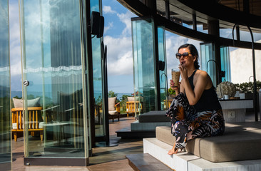 Charming young woman sits in hotel cafe and enjoying the view