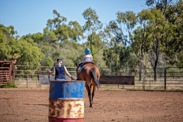 Woman Leading Young Girl On Horseback To Compete In Barrel Race