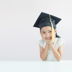 Portrait little Asian girl is wearing graduate hat and smile with happiness select focus shallow depth of field with copy space for education concept
