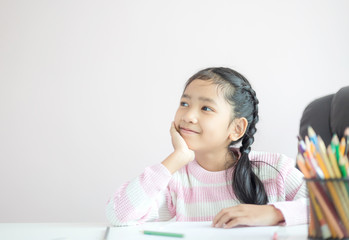 Portrait little Asian girl sitting on the chin and smile with happiness metaphor thinking someting...
