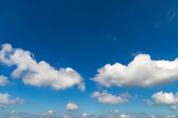 White fluffy clouds over a deep blue sky beautiful summer air background