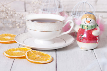 A cup of tea, a snowman toy and slices of orange