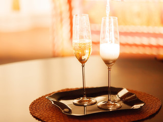 Two tall glasses of sparkling wine on small tray