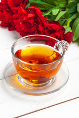 Glass kettle of herbal tea with fresh flowers close up