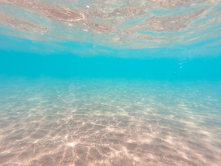 Fototapeta na wymiar underwater background with sandy sea bottom. Beautiful texture of the sea and ocean water. Pure water texture.