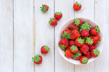 BOWL FULL OF FRESH STRAWBERRIES ON WHITE WOOD BACKGROUND