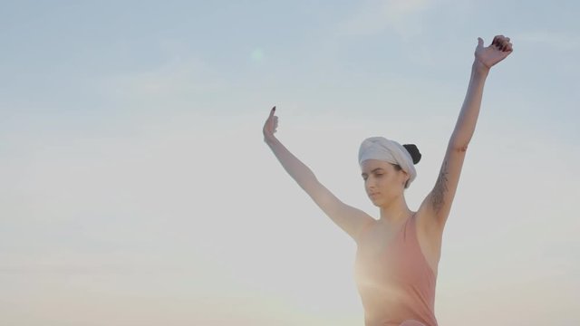 A girl in a turban is practicing a special breathing practice. She quickly inhales and exhales the air, the vibration of the chest. Arms raised, turban on the head, eyes closed, lotus pose, namaste.