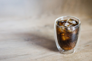 glass of cola with ice on wooden table background with copy space