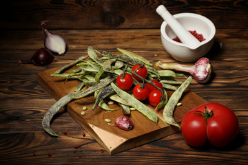 Greenbeans and cherry tomatoes in a wooden board on a rustic table.