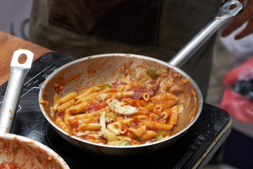 cooking food of italian cuisine, pasta Penne with tomato sauce, detailed view of spoon and pan frying