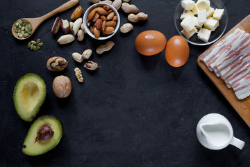Fototapeta na wymiar Keto food: avocado, eggs, butter, bacon, nuts on dark background. 