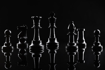 Chess figures on dark black background close up