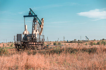 Fototapeta premium Oil well site pump jack and fields at in rural