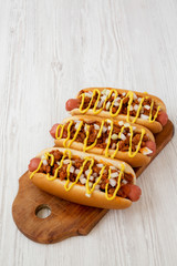 Homemade detroit style chili dog on a rustic wooden board on a white wooden background, low angle view. Copy space.