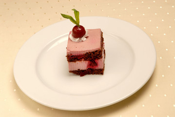 Delicious Cheesecake. A slice of cake on a plate of cherries