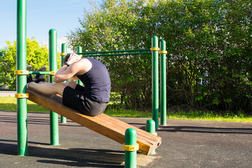 Fototapeta premium a man goes in for sports outdoors, on a special platform, does an exercise on a press