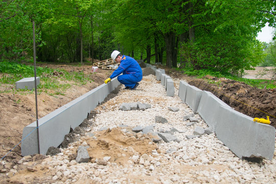 working moments Mester in blue uniform, when laying new roads for pedestrians, in compliance with the norms and hydro