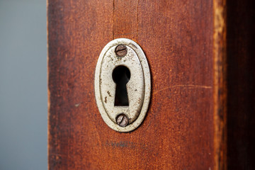 Old metal keyhole in wooden door, macro shot