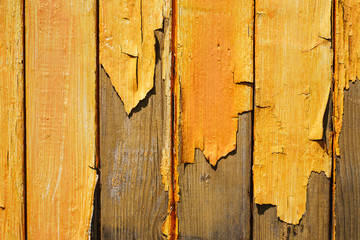 Old wooden fence with yellow peeling paint texture