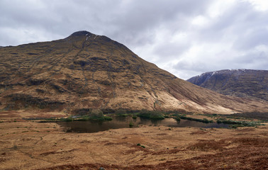 Fototapeta na wymiar Small Islands dot the Loch on the Valley floor of Glen Etive, in the Scottish Highlands. This Loch is overlooked by one of the many Mountains.
