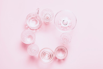 Many empty glasses on pink background. Top view, flat lay.