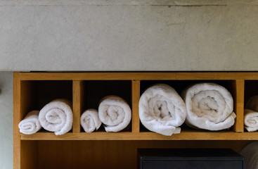 Roll white soft towels in built in wooden shelf