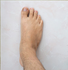 Selective focus. Male feet on faience  floor (tile)